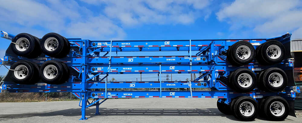 A medium, horizontal shot shows three bright blue container chassis trailers stacked on top of each other outdoors.