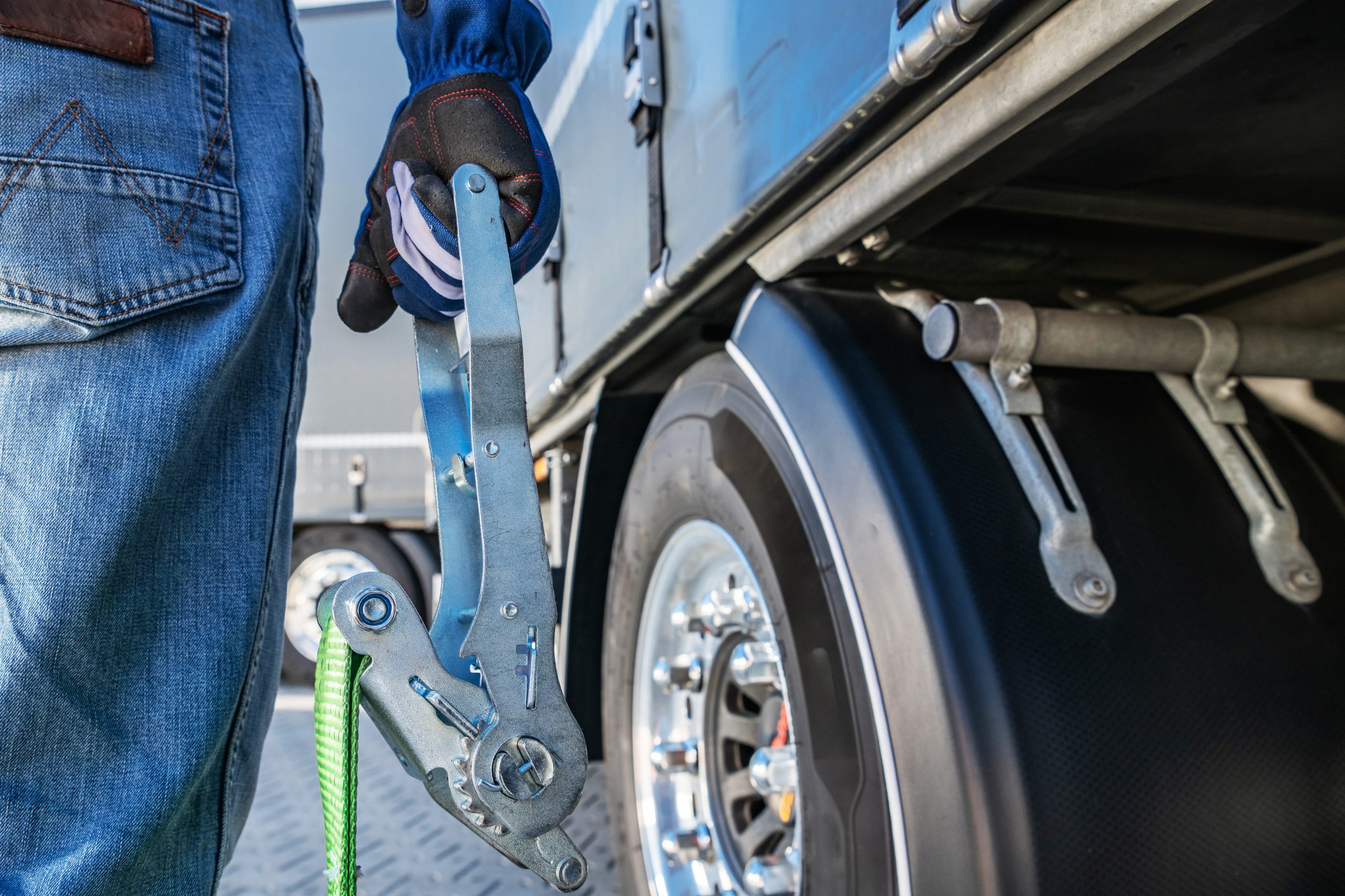 Man Securing a Cargo Strap on a Truck at a Loading Dock During Daylight