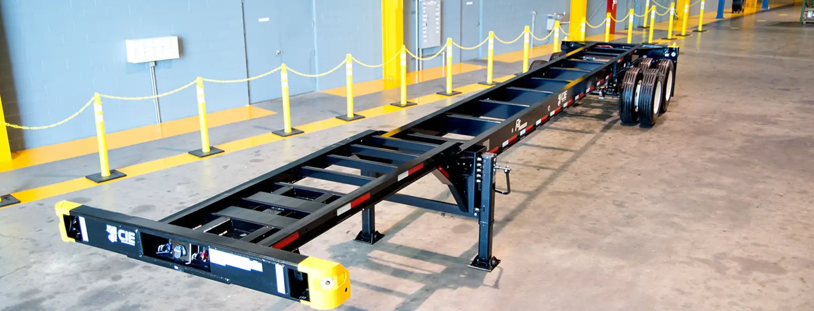CIE Pioneer Chassis angled side view showing full frame and dual axle wheels inside factory