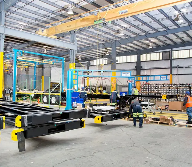 Overhead crane lifting container chassis at CIE Manufacturing